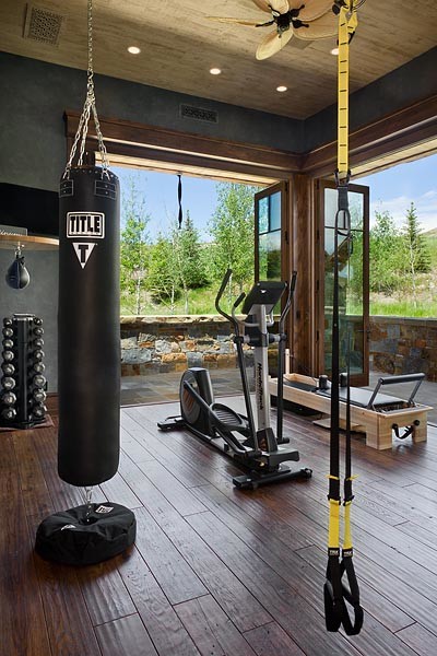 Multifunktionaler Uriger Fitnessraum mit grauer Wandfarbe und dunklem Holzboden in Sonstige