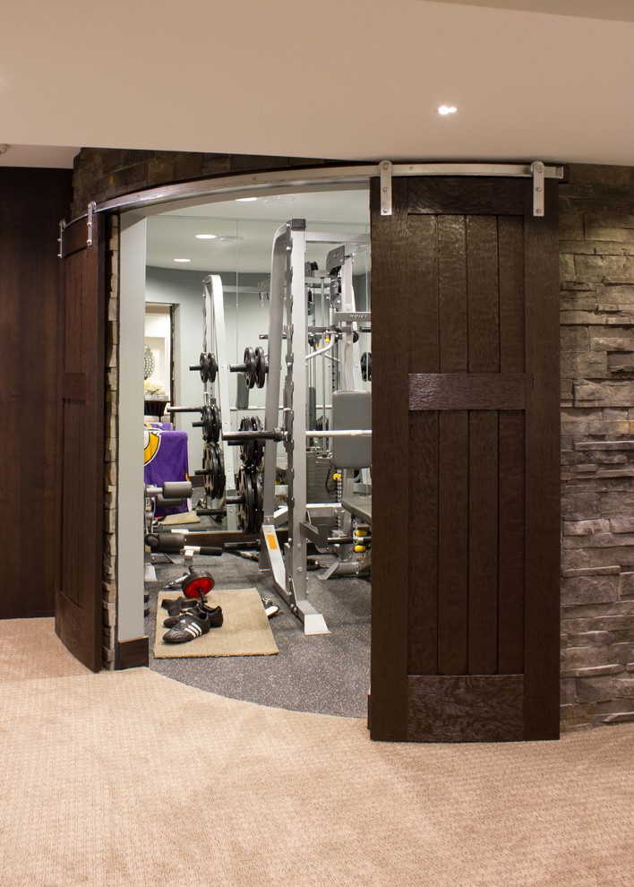 Imagen de sala de pesas actual de tamaño medio con paredes grises y moqueta