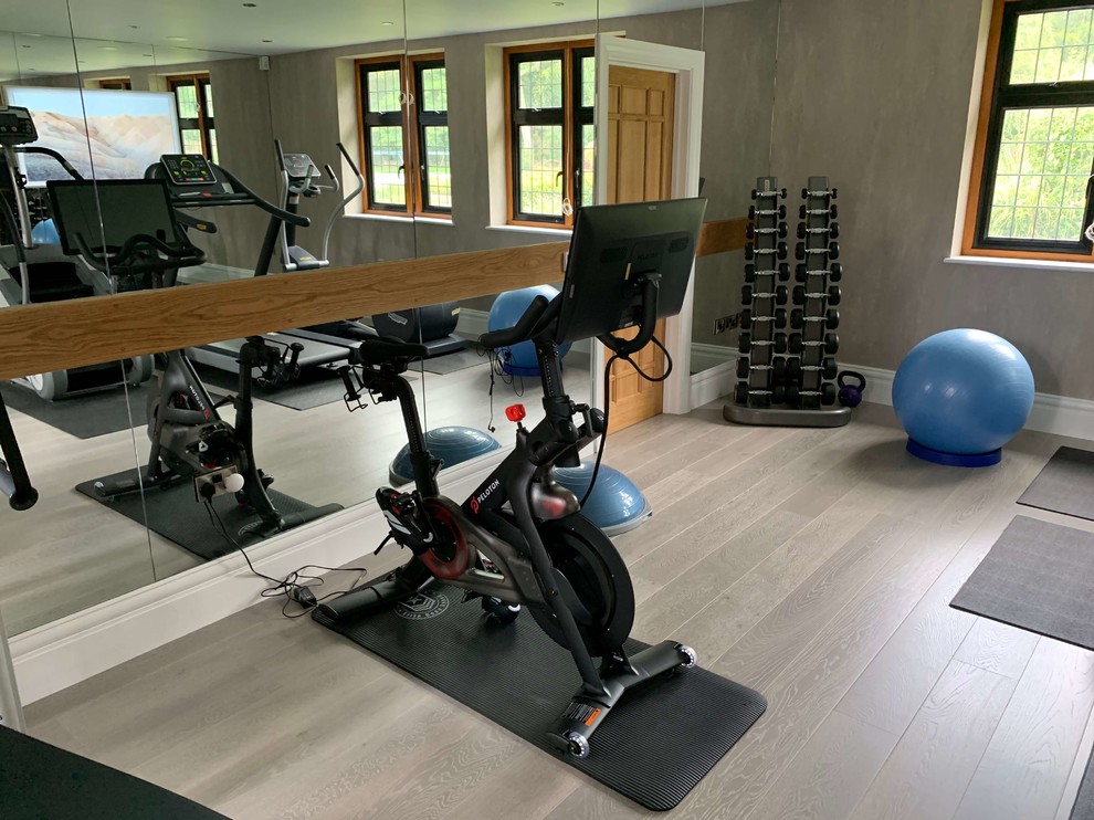 Medium sized contemporary home weight room in Hertfordshire with grey walls, painted wood flooring and beige floors.