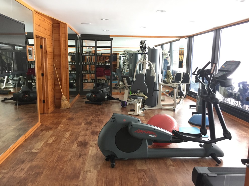 Foto de sala de pesas rústica de tamaño medio con paredes marrones, suelo de madera en tonos medios y suelo marrón