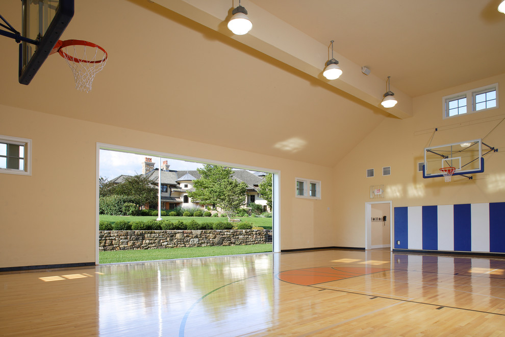 Großer Klassischer Fitnessraum mit Indoor-Sportplatz, gelber Wandfarbe, hellem Holzboden und beigem Boden in New York