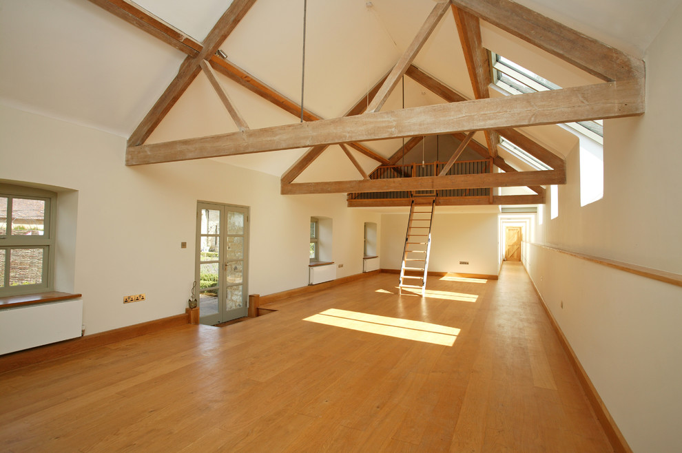 Photo of a farmhouse multi-use home gym in Dorset with white walls and light hardwood flooring.