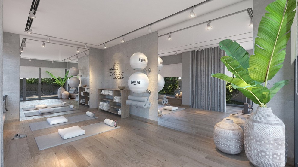 Idée de décoration pour un grand studio de yoga design avec un mur gris, parquet clair et un sol marron.
