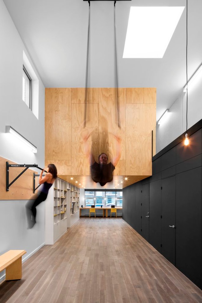 Diseño de sala de pesas contemporánea grande con paredes blancas, suelo de madera en tonos medios y suelo multicolor