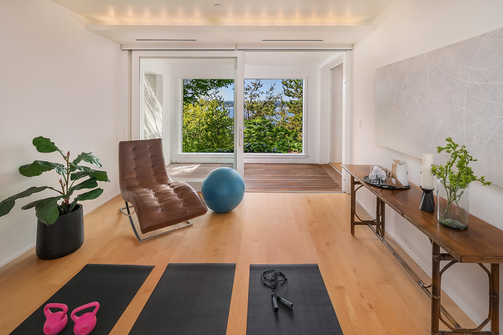 Diseño de estudio de yoga costero con paredes blancas, suelo de madera en tonos medios y suelo marrón
