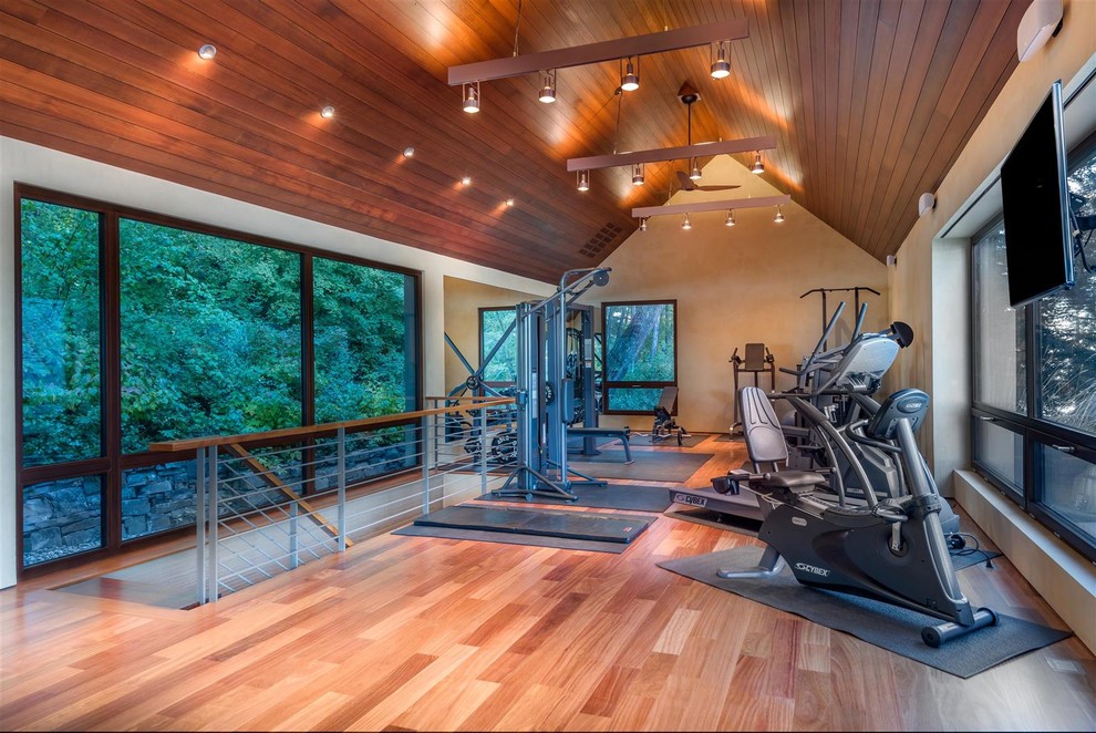 Moderner Fitnessraum mit beiger Wandfarbe und braunem Holzboden in Sonstige