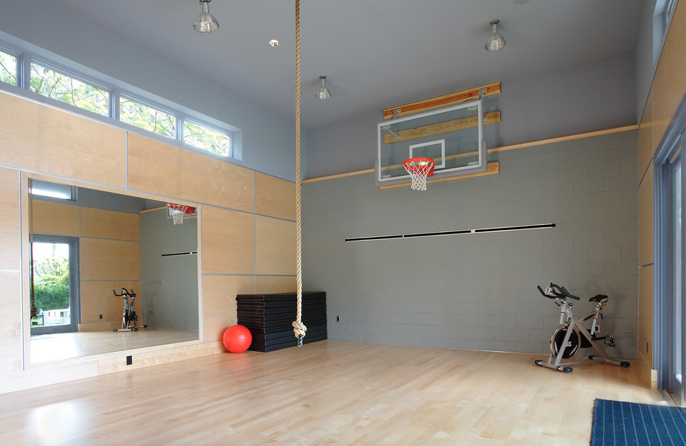 Aménagement d'un grand terrain de sport intérieur moderne avec un mur gris et parquet clair.