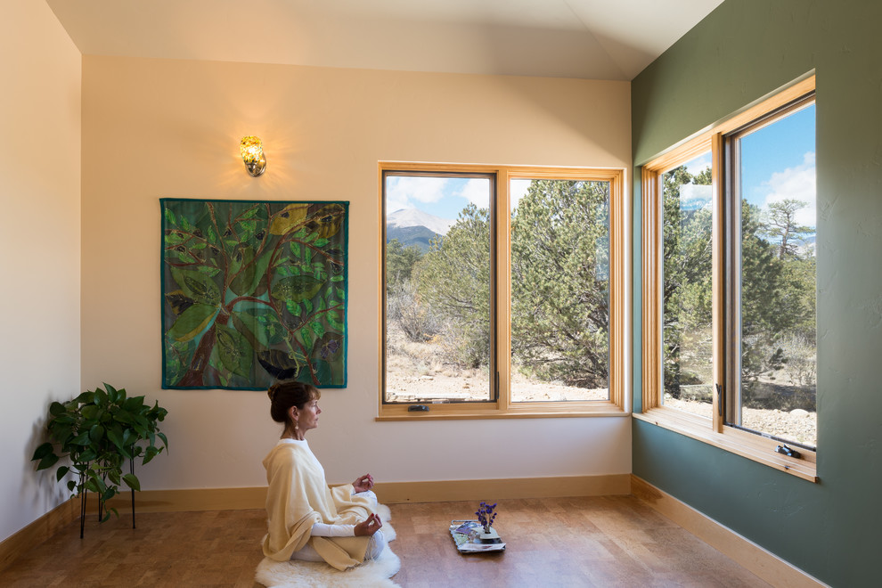 Imagen de estudio de yoga minimalista grande con paredes verdes y suelo de madera en tonos medios