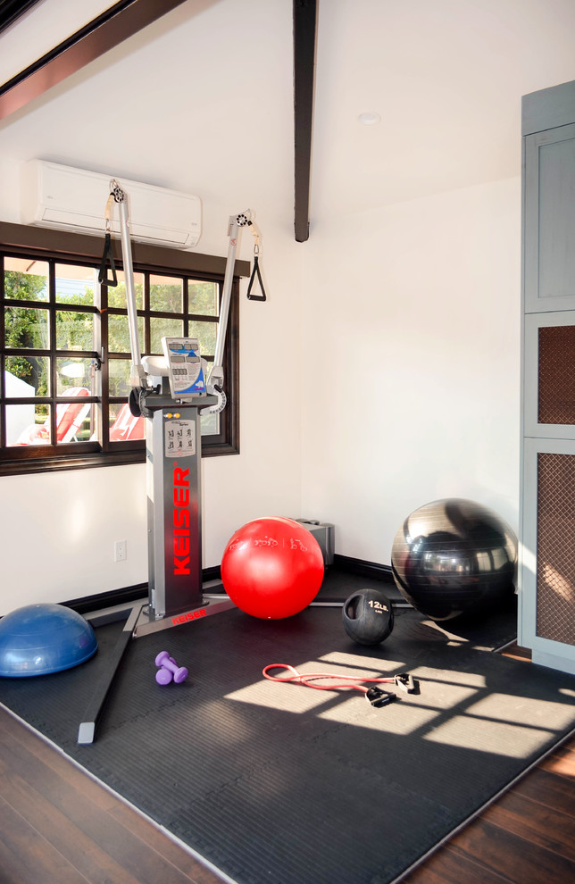 Photo of a medium sized mediterranean multi-use home gym in Los Angeles with white walls, laminate floors and brown floors.