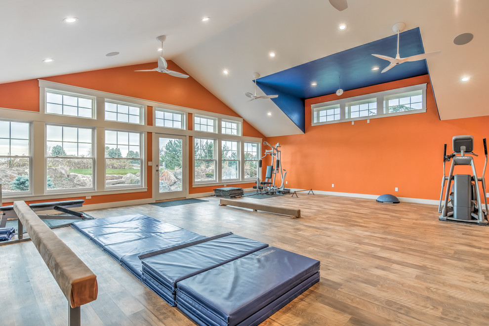 Multiuse home gym - large medium tone wood floor multiuse home gym idea in Boise with orange walls