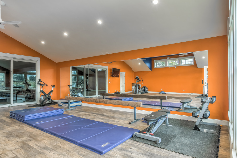 Large traditional multi-use home gym in Boise with orange walls and medium hardwood flooring.