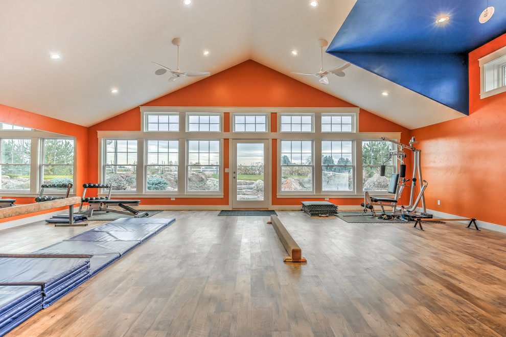 Immagine di una grande palestra multiuso design con pareti arancioni e pavimento in legno massello medio