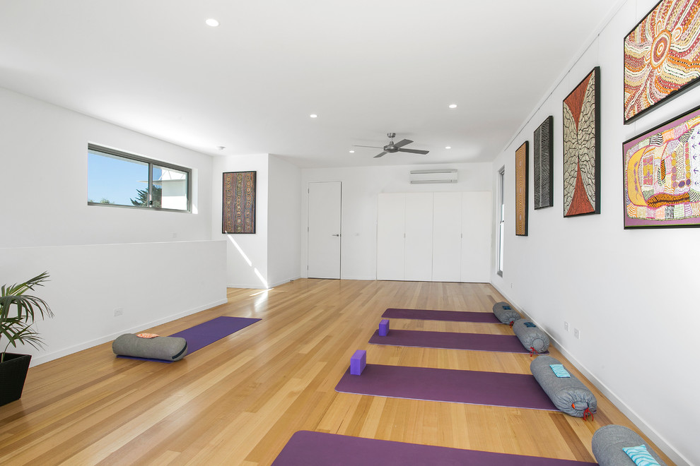 Diseño de estudio de yoga actual con paredes blancas y suelo de madera clara