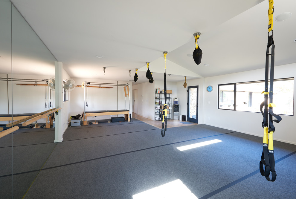 На фото: универсальный домашний тренажерный зал среднего размера в стиле модернизм с белыми стенами и серым полом с