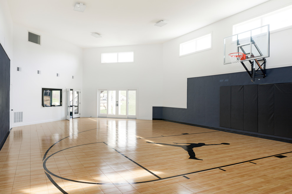 Großer Moderner Fitnessraum mit Indoor-Sportplatz, weißer Wandfarbe, Laminat und braunem Boden in Minneapolis