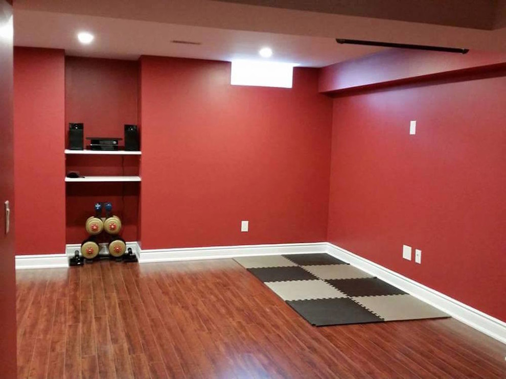 Foto de gimnasio multiusos actual de tamaño medio con paredes rojas, suelo de madera en tonos medios y suelo marrón