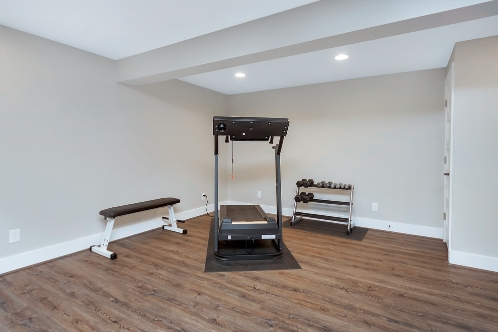 Example of a mid-sized classic medium tone wood floor and brown floor home weight room design in DC Metro with gray walls