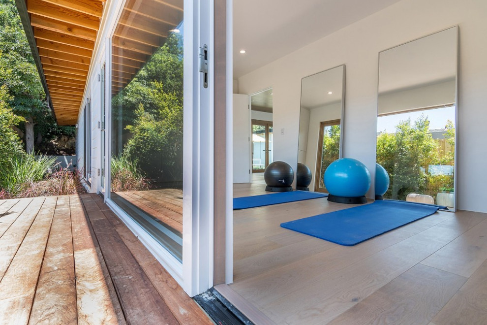 Mittelgroßer Mid-Century Yogaraum mit weißer Wandfarbe, braunem Holzboden und braunem Boden in Los Angeles