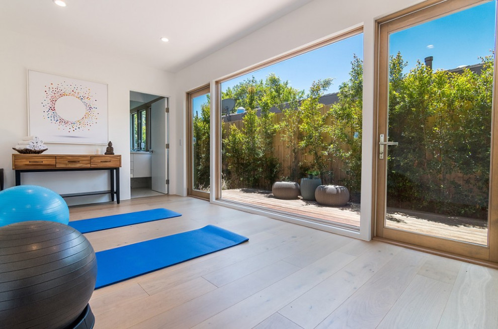 Cette photo montre un studio de yoga rétro de taille moyenne avec un mur blanc, un sol en bois brun et un sol marron.