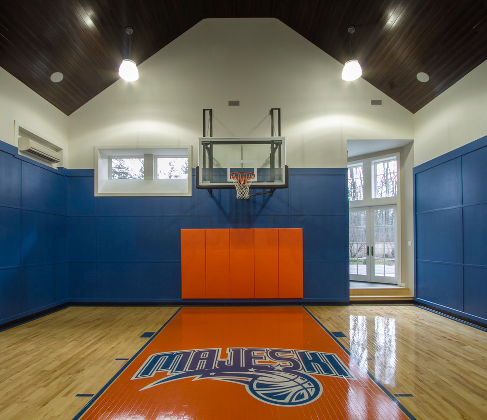 Großer Klassischer Fitnessraum mit Indoor-Sportplatz, blauer Wandfarbe und hellem Holzboden in New York