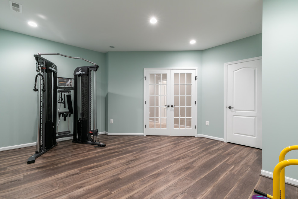 Imagen de sala de pesas clásica renovada de tamaño medio con paredes azules, suelo vinílico y suelo marrón