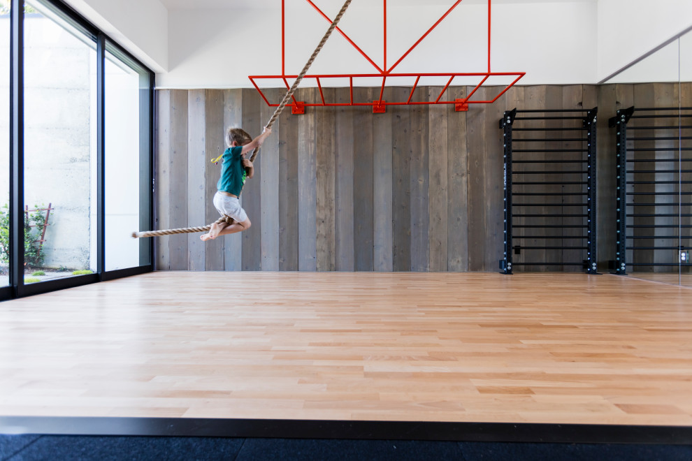 Multifunktionaler, Großer Moderner Fitnessraum mit weißer Wandfarbe, hellem Holzboden und beigem Boden in Seattle