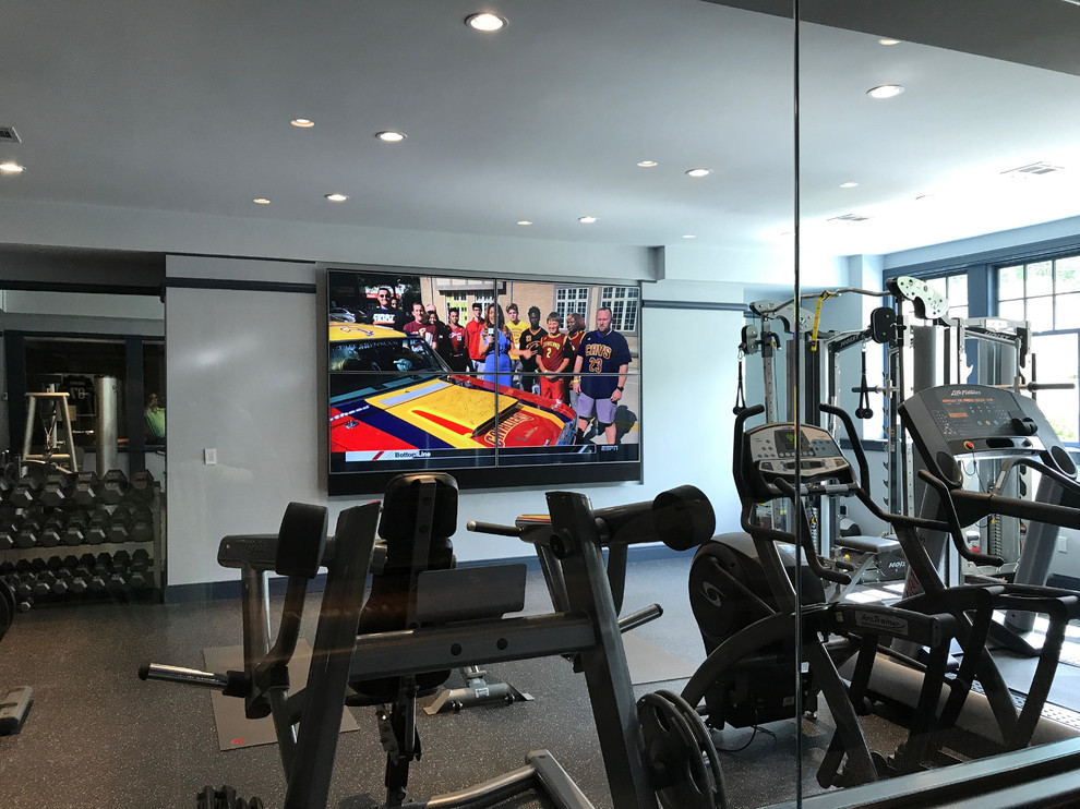 Aménagement d'une grande salle de musculation classique avec un mur gris et un sol gris.