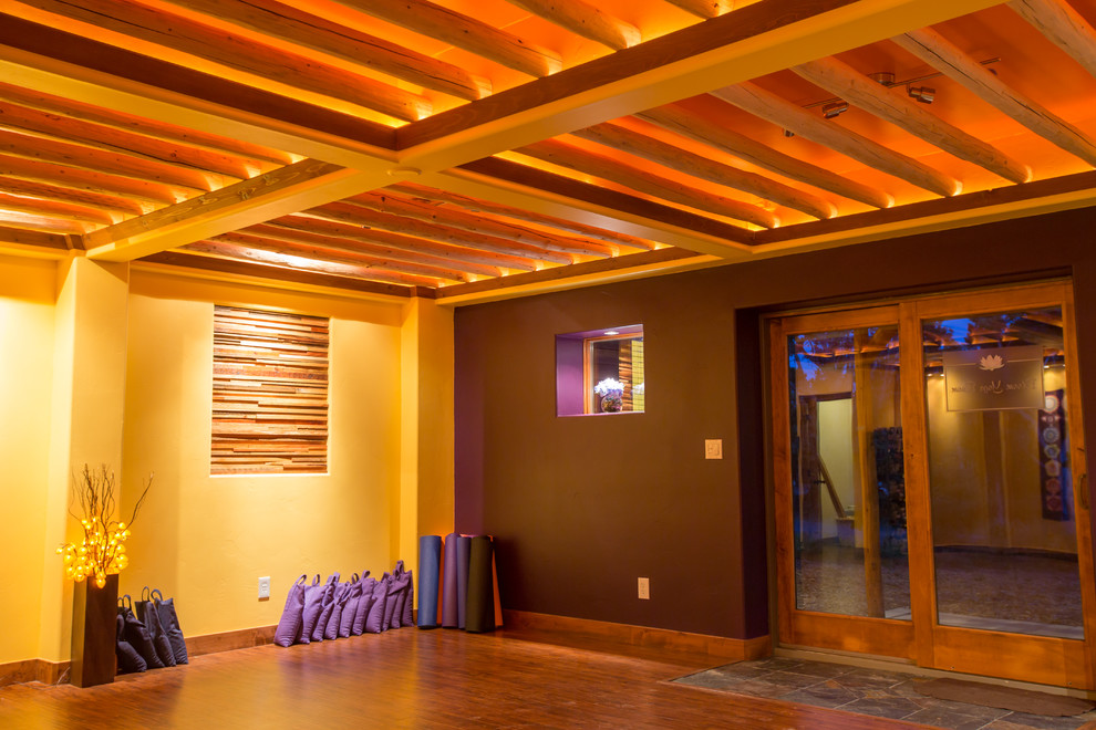Foto de estudio de yoga rural grande con paredes púrpuras, suelo de madera en tonos medios y suelo marrón