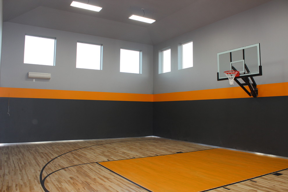 Exemple d'un grand terrain de sport intérieur craftsman avec un mur gris et un sol en bois brun.