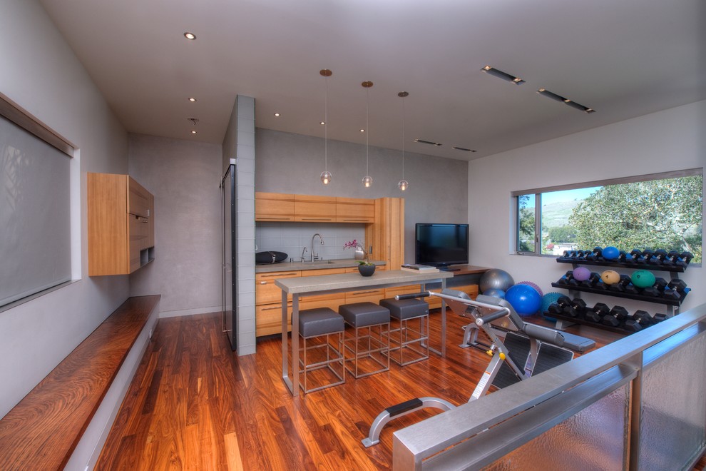 This is an example of a contemporary multi-use home gym in San Francisco with grey walls, medium hardwood flooring, orange floors and feature lighting.