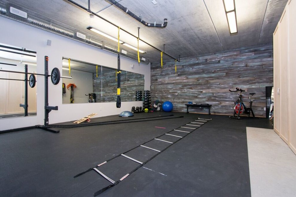 Ejemplo de gimnasio multiusos tradicional renovado grande con paredes grises, suelo de corcho y suelo negro