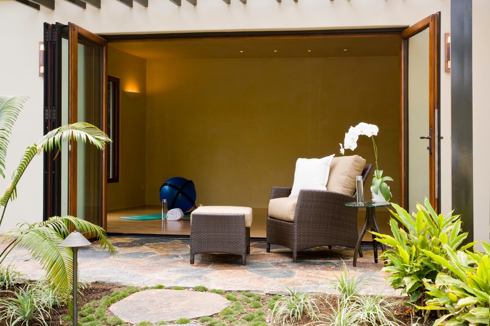 Diseño de estudio de yoga tropical de tamaño medio con paredes beige, suelo de madera clara y suelo beige