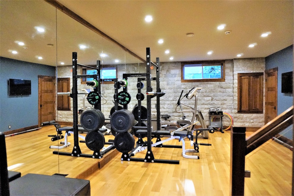 Imagen de sala de pesas rural de tamaño medio con paredes grises, suelo de madera clara y suelo beige