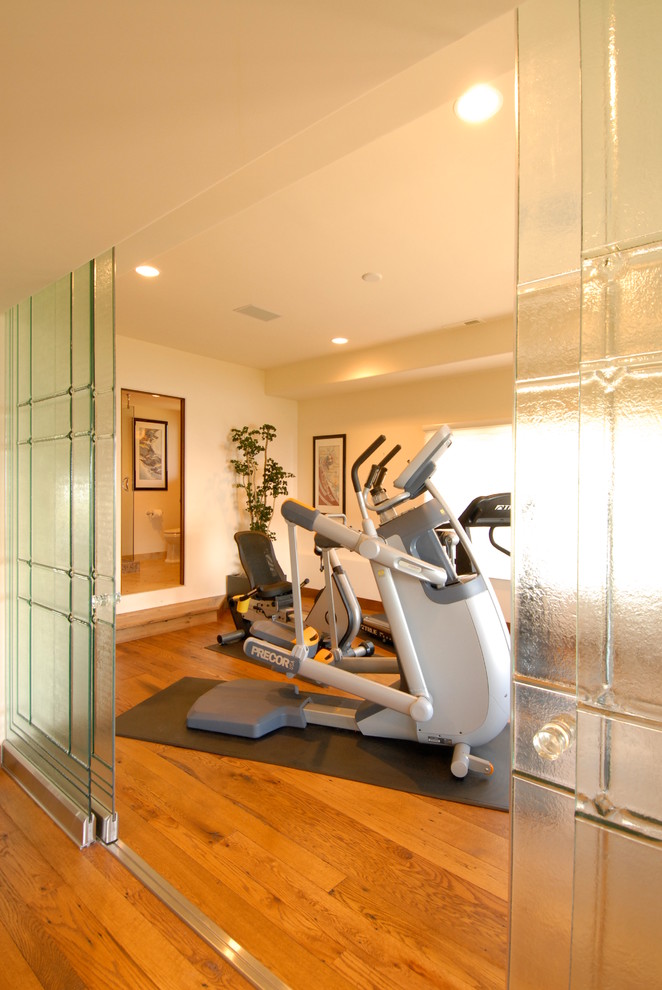 Multifunktionaler, Großer Moderner Fitnessraum mit beiger Wandfarbe und braunem Holzboden in Sonstige