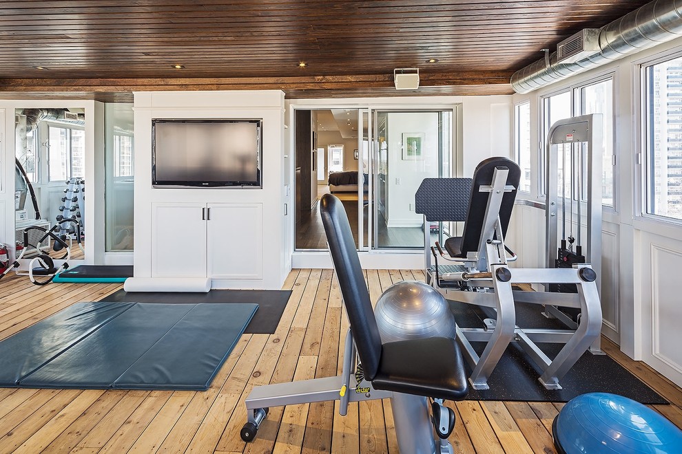 This is an example of a large traditional multi-use home gym in Toronto with white walls and medium hardwood flooring.