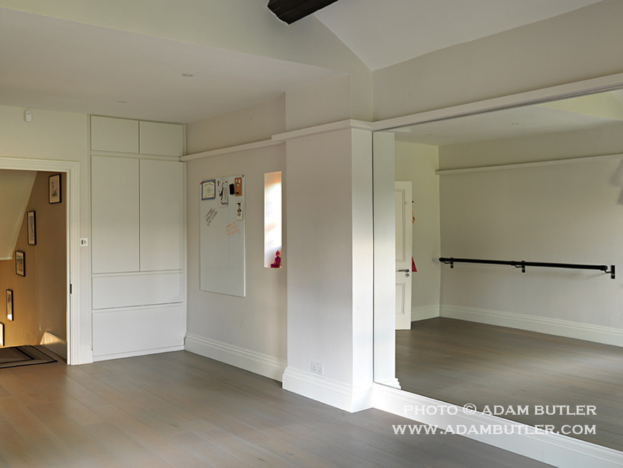 This is an example of a large contemporary home yoga studio in London with white walls and medium hardwood flooring.