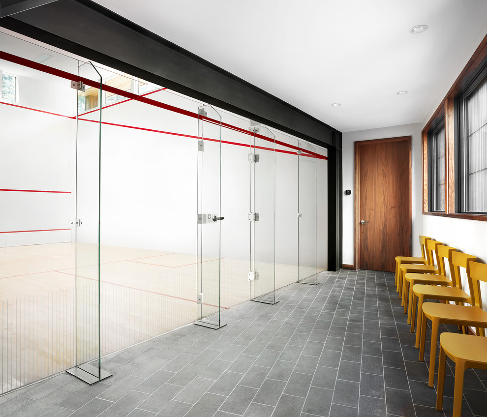 Idée de décoration pour un très grand terrain de sport intérieur minimaliste avec un mur blanc, sol en stratifié et un sol marron.