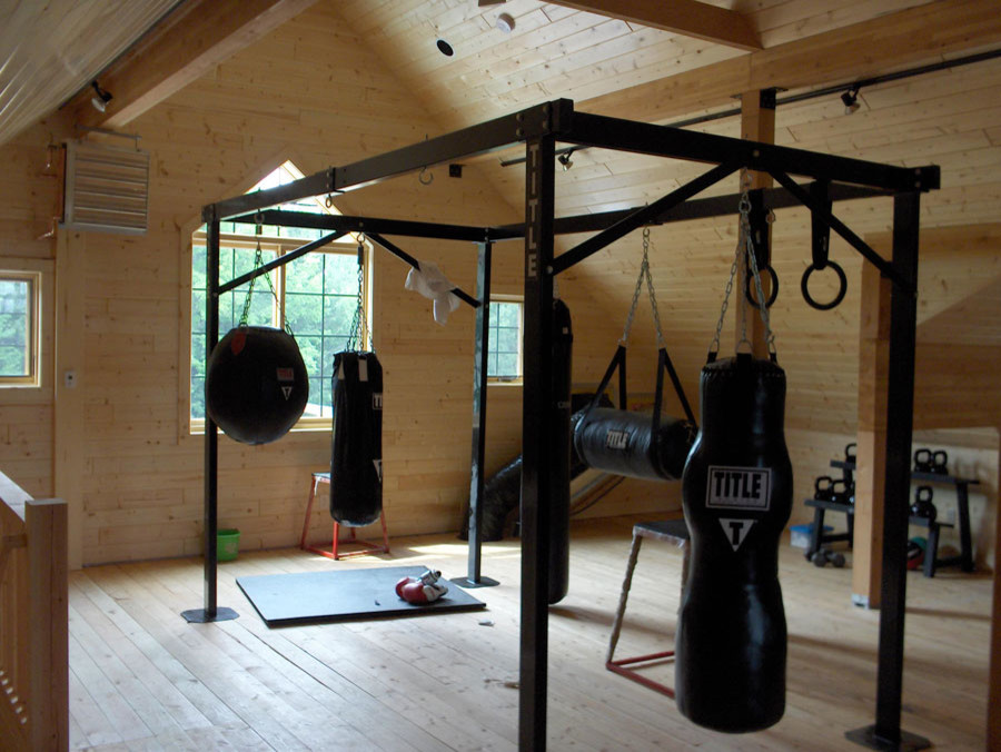 Modelo de sala de pesas rural grande con paredes marrones y suelo de madera en tonos medios