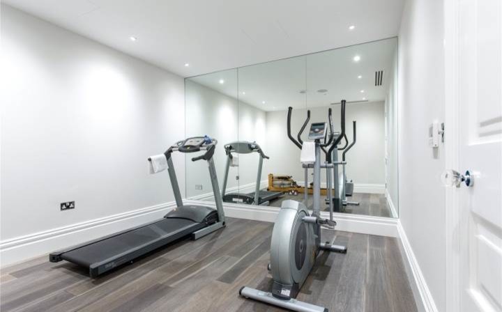 Mittelgroßer, Multifunktionaler Moderner Fitnessraum mit weißer Wandfarbe und braunem Holzboden in London