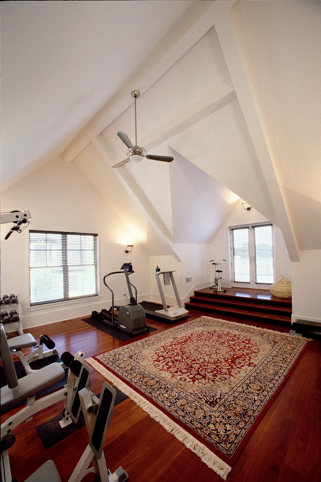 Exemple d'une salle de musculation chic de taille moyenne avec un mur blanc, parquet foncé et un sol marron.