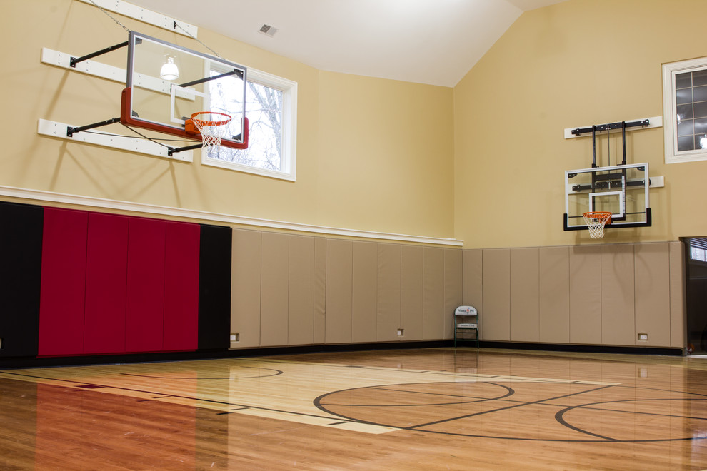 Großer Moderner Fitnessraum mit Indoor-Sportplatz, braunem Holzboden, gelber Wandfarbe und braunem Boden in Chicago