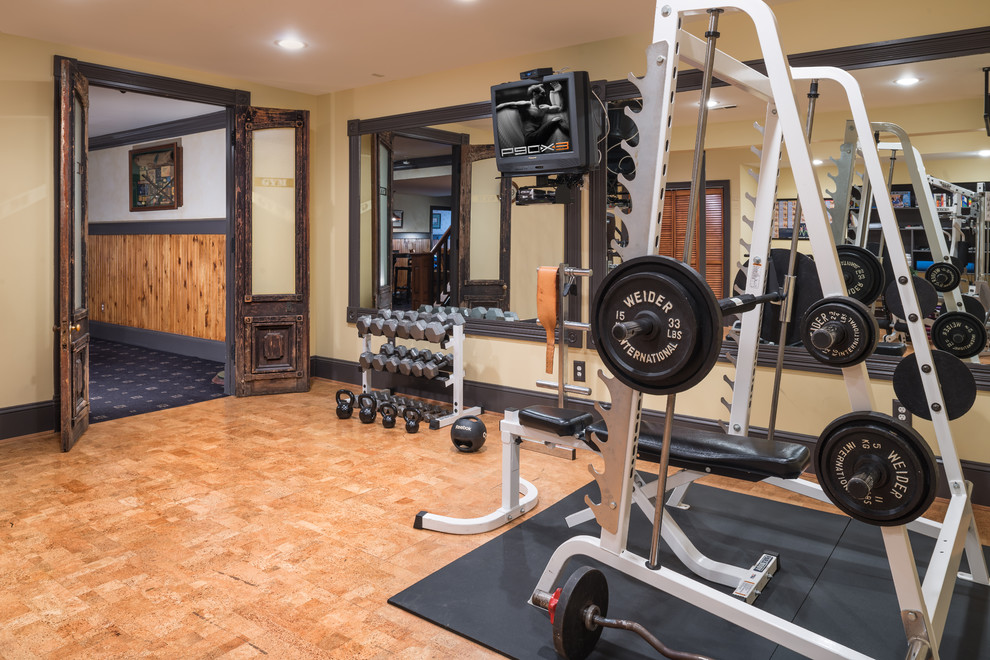 Cette image montre une salle de musculation traditionnelle de taille moyenne avec un mur beige, un sol en liège et un sol marron.