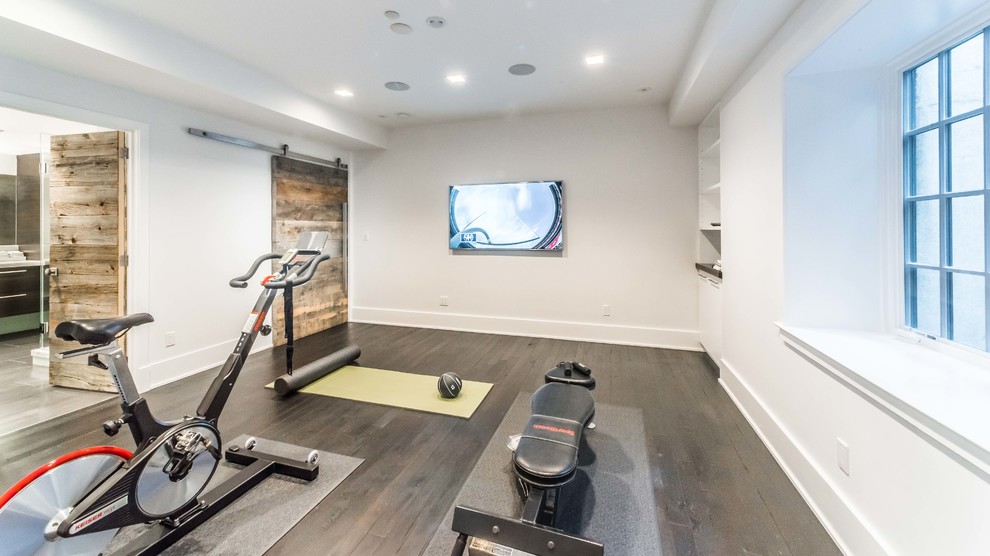 Example of a large minimalist dark wood floor multiuse home gym design in New York with white walls