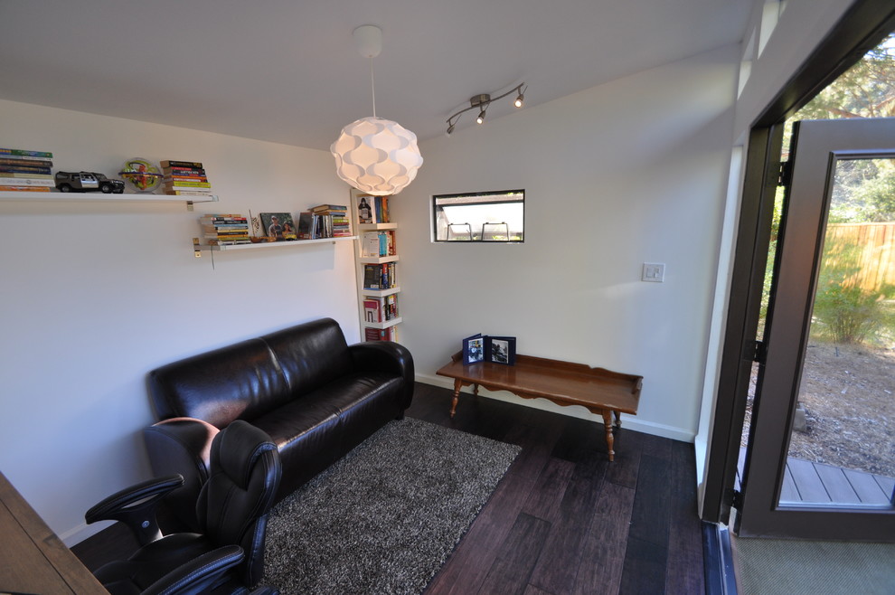 Réalisation d'un bureau minimaliste avec un mur blanc et parquet foncé.