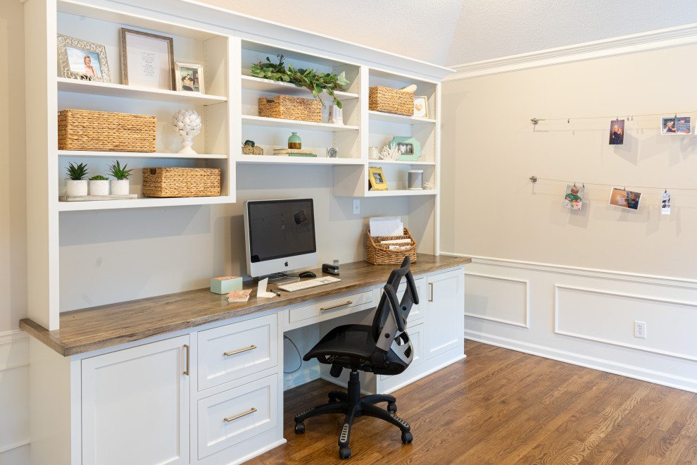 Modelo de despacho tradicional renovado de tamaño medio con paredes blancas, suelo de madera en tonos medios y escritorio empotrado