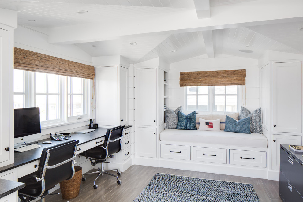 This is an example of a coastal study in Orange County with white walls and a built-in desk.