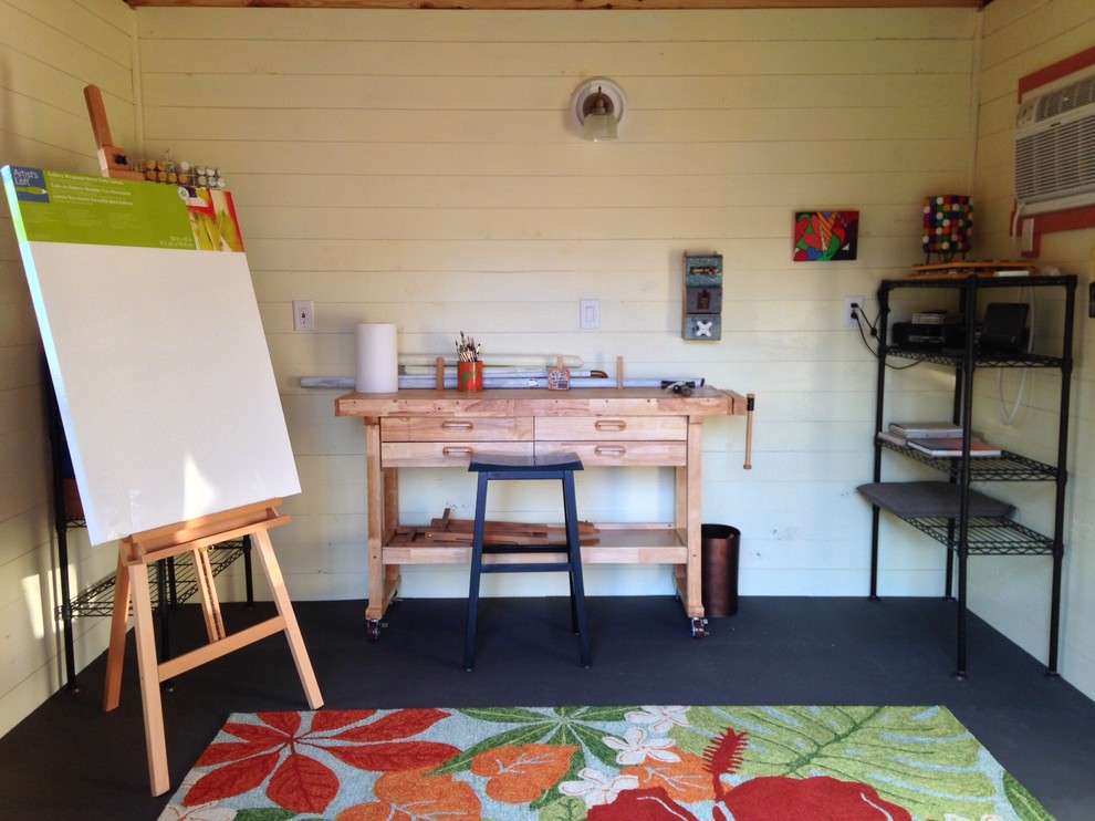 Imagen de estudio de estilo americano pequeño sin chimenea con paredes blancas, suelo de cemento, escritorio independiente y suelo negro