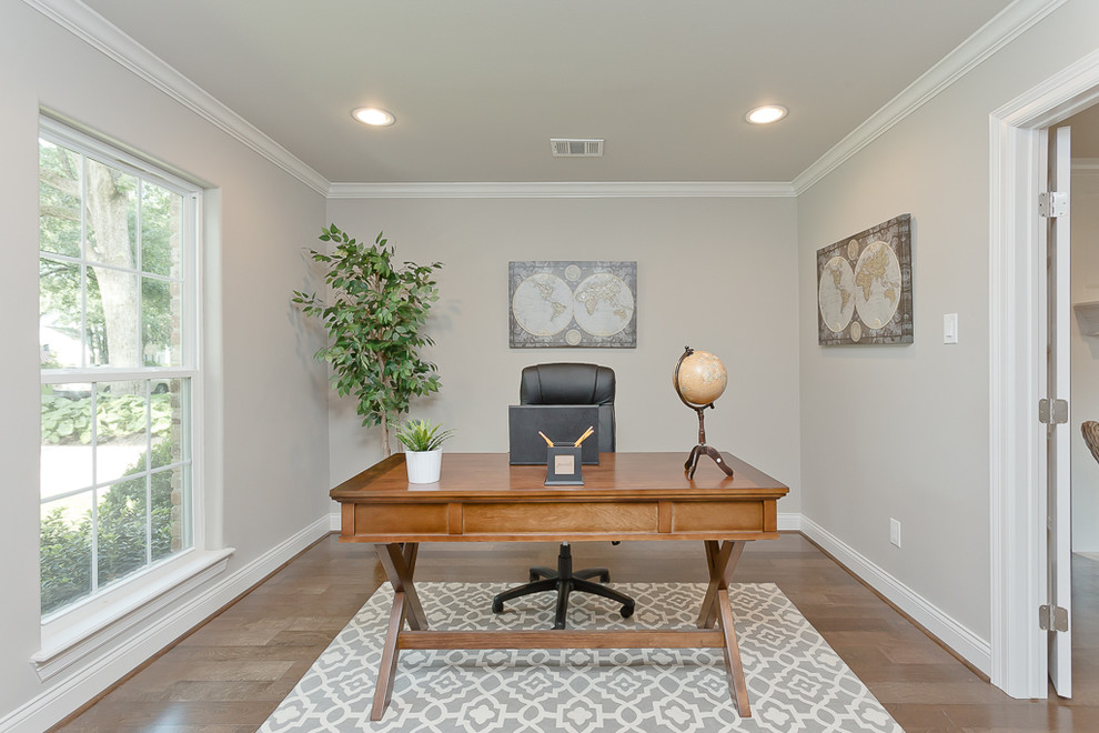 Elegant freestanding desk medium tone wood floor study room photo in Houston with gray walls