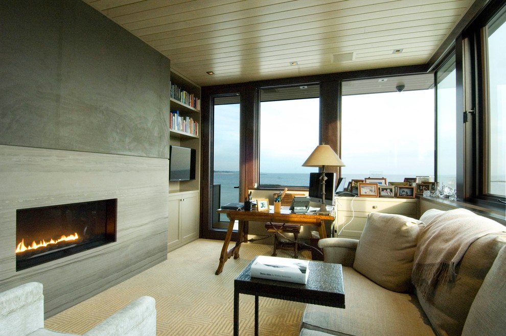 This is an example of a medium sized contemporary study in New York with a ribbon fireplace, a stone fireplace surround and a freestanding desk.