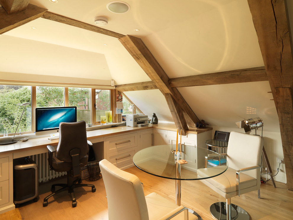 Study room - large country built-in desk medium tone wood floor study room idea in Hampshire with beige walls